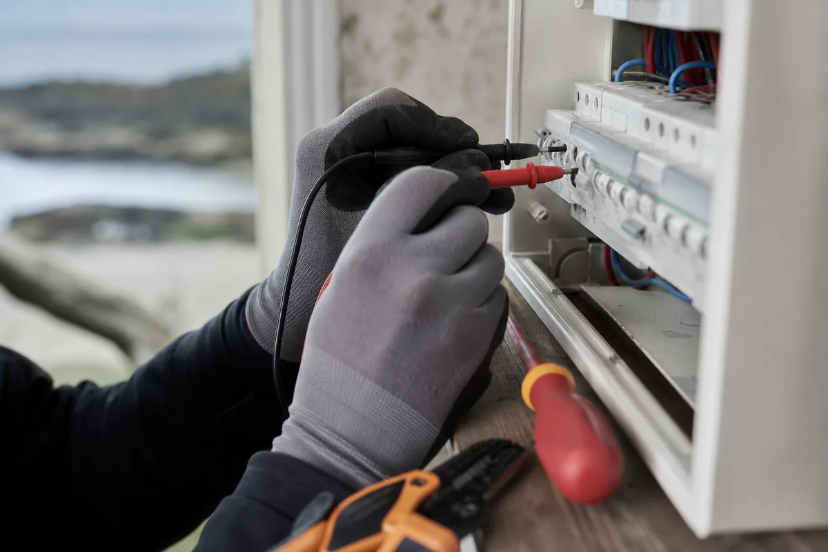 Mains d&rsquo;électricien mesurant la tension sur un circuit avec un multimètre